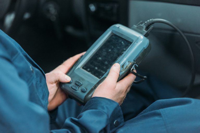 Cropped shot of automechanic using a car diagnostic tool in a service workshop.